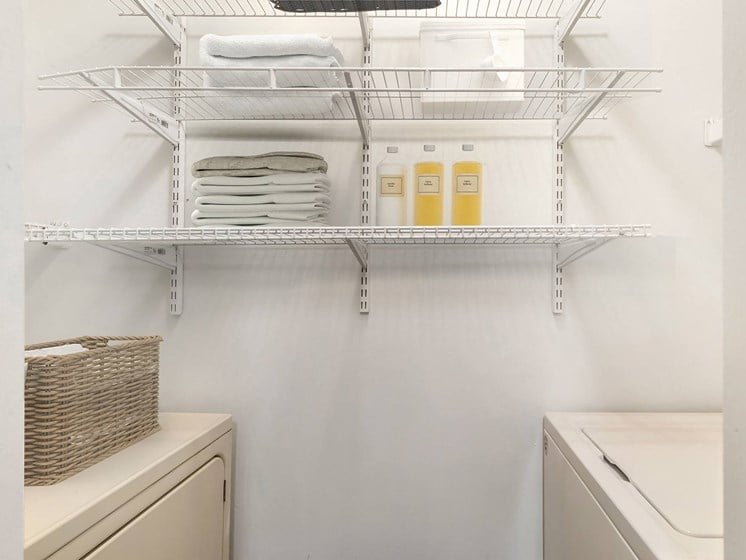 a laundry room with a sink and a shelf with towels